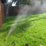 irrigation installation in New England with a brown fence and green lawn in Marblehead