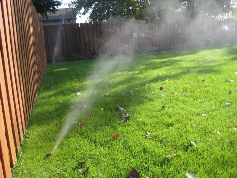 irrigation installation in New England with a brown fence and green lawn in Marblehead